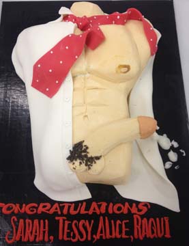 A cake designed to resemble a male torso, wearing a white shirt and a red polka dot tie. Text on the cake reads Congratulations Sarah, Tessy, Alice, Raqui.